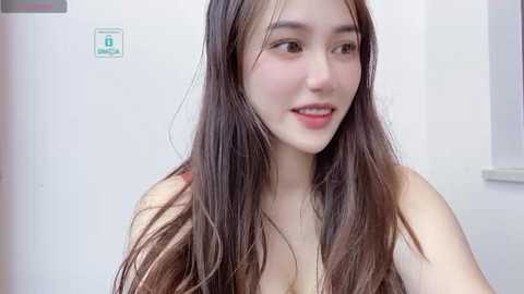 Media: Video of an East Asian woman with long, straight brown hair, fair skin, and small breasts, smiling, wearing a sleeveless top, against a white background.