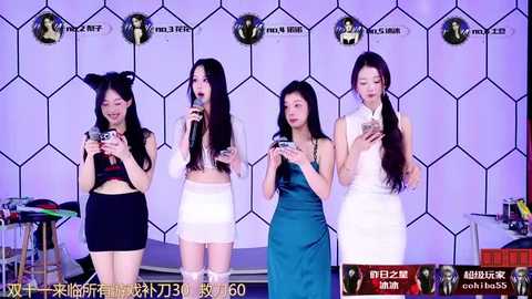 Media: Video of four East Asian women in white dresses, holding microphones, singing on stage against a hexagonal patterned background.