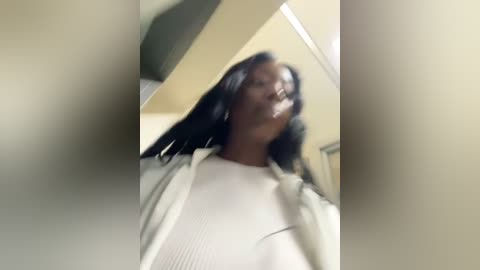 Media: A blurred, low-quality video of a Black woman with long, straight hair in a white sweater, taken from a close-up angle.