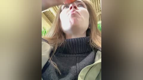 Media: A video shows a young woman with fair skin and long brown hair, wearing a grey sweater, with her head tilted back, seemingly looking at something above her.