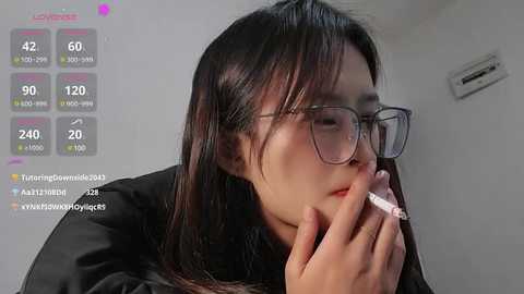 Media: Video of a young Asian woman with long black hair, wearing glasses, smoking, with a live stream overlay showing chat messages.