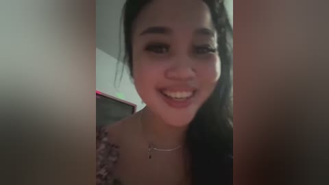 Media: A close-up video of a smiling Asian woman with long black hair, wearing a floral-patterned top and a silver necklace.