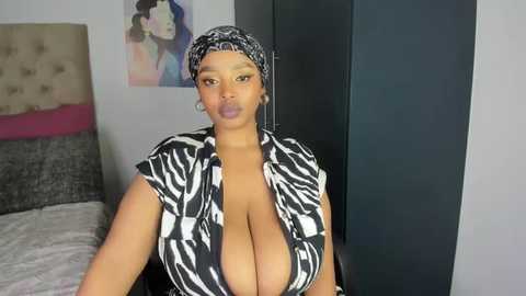 Media: Video of a curvy Black woman with large breasts, wearing a zebra-print top, in a modern bedroom with a zebra-patterned headscarf.