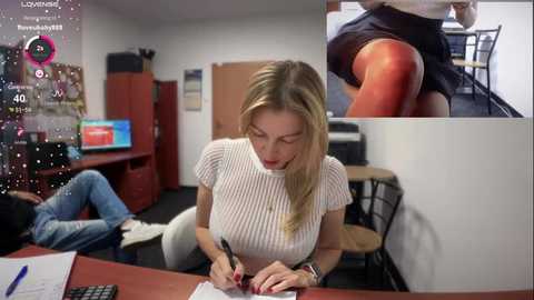 Media: Video of a blonde woman in a white knit top, sitting at a desk, typing on a laptop. Background shows a room with a red cabinet, computer, and a man in jeans and a hoodie. Overlayed are two close-up images of her.