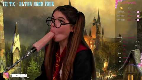 Media: Video of a young woman with long brown hair, wearing glasses, a Hogwarts school uniform, and a red tie, licking a large, realistic, pink dildo, set against a digital background of Hogwarts Castle.