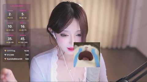 Media: A young East Asian woman with fair skin and long dark hair, wearing headphones, sits in a dimly lit room, focused on a phone screen displaying a blue and white image of an open mouth.