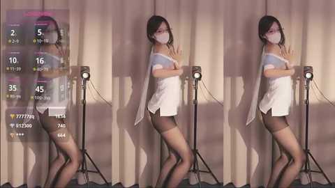 Media: Video of an Asian woman in a white dress, black stockings, and mask, standing in front of a camera with a white backdrop.