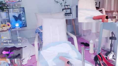 Media: A video of a disorganized room with a white recliner chair, pink blanket, and scattered objects, including a video game controller, on a purple floor.