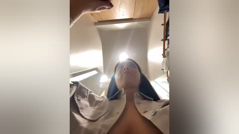 Media: Video of a woman in a bathtub, covered in a white towel, with a bright light shining from above, creating a dramatic effect.