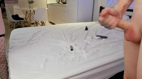 Media: Video of a man punching a white mattress, causing a dent. Background shows a minimalist, modern bedroom with a white dresser, chair, and pink carpet.