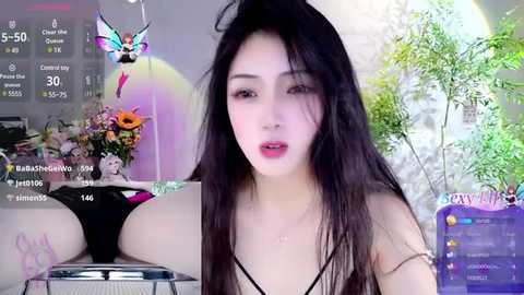 Media: A video of an East Asian woman with long black hair and pale skin, wearing black lingerie, sitting in front of a computer screen with a virtual sun, flower, and butterfly decorations.