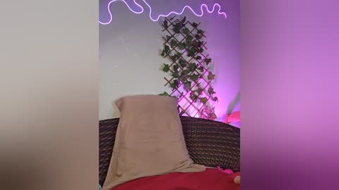 Media: A video of a cozy bedroom with a wicker headboard, beige pillow, and a red blanket, featuring a green leafy wall decor and purple neon lights.