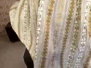 Media: Video of a person wearing a striped, patterned shirt with a delicate lace collar, partially visible dark fabric underneath, and a beige, textured background.