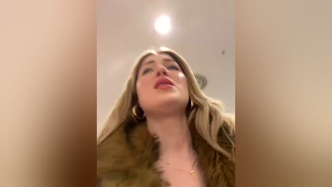 Media: A video of a young woman with long, blonde hair, wearing a brown fur coat, captured from a low angle, looking upward.