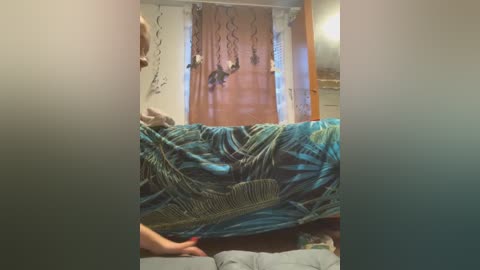 Media: Video of a cozy bedroom with a turquoise bedspread, wooden door, and fairy lights. A person's hand holds a feather duster.