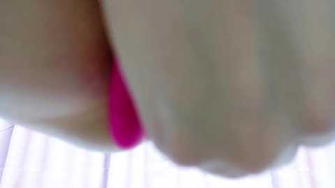 Media: Video of a close-up of a woman's thighs and buttocks, with bright pink panties visible. The background is blurry, suggesting an indoor setting with soft, diffuse lighting. The image focuses on the woman's lower body, highlighting the color contrast between the skin tone and the vibrant underwear.