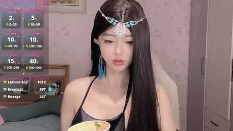 Media: Video of a young Asian woman with long black hair, wearing a blue headband and black lingerie, holding a lemon in a bedroom.