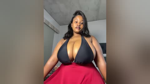 Media: A video of a plus-size Black woman with a voluptuous figure wearing a black halter top and red skirt, posing indoors with exposed concrete ceiling.