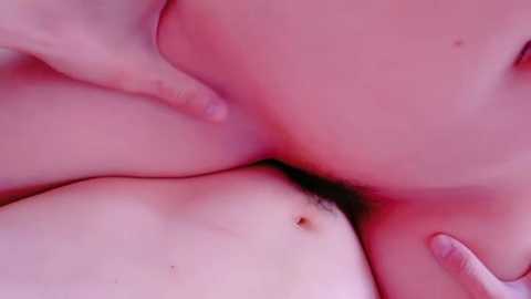 Media: Close-up video of two nude people with fair skin, embracing in a sensual manner. The image is soft-focused, emphasizing the pinkish hue of their skin and the natural curves of their bodies.