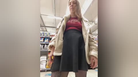 Media: A video of a young woman in a supermarket, wearing a beige jacket, black skirt, and maroon top with \"Mars\" logo, shopping with a cart.