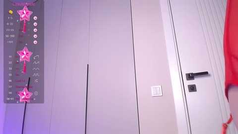 Media: A video of a modern, minimalist bathroom featuring white walls, a closed door, and a temperature control panel with pink star stickers.