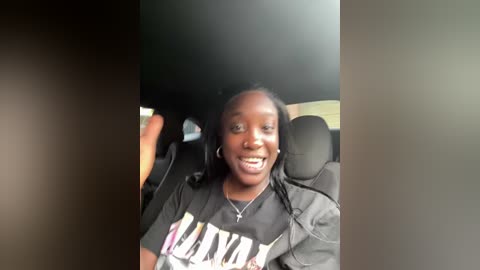 Media: A video of a smiling young Black woman with braided hair in a black t-shirt, wearing headphones, sitting in a car.