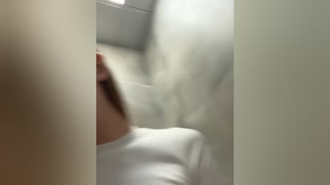 Media: A blurred video showing a person with light skin, possibly a woman, wearing a white shirt, and a white background, possibly a hospital room.