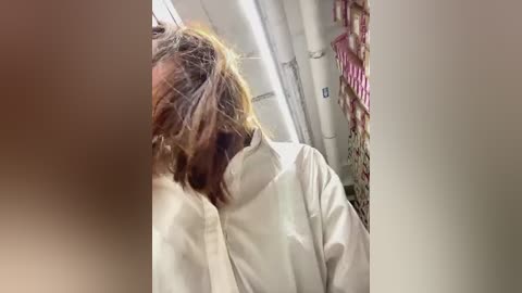 Media: Video of a disheveled man in a white lab coat, with messy hair, standing in a cluttered room with pipes and pink fabric hanging in the background.