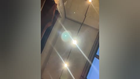 Media: A video showing a ceiling with light reflections from multiple small, bright lights, creating a starburst effect. The background reveals a glimpse of a window with blue sky and curtains.