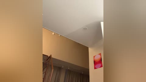 Media: Video of a modern, minimalist hallway with beige walls and a white ceiling. A red abstract art piece hangs on the right wall, and a wooden staircase with metal railings is visible on the left. The lighting is soft, creating a serene atmosphere.