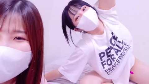 Media: Video of an Asian woman with straight black hair and fair skin, wearing a white mask, T-shirt, and panties. She's posing provocatively on a bed with a blurred background.