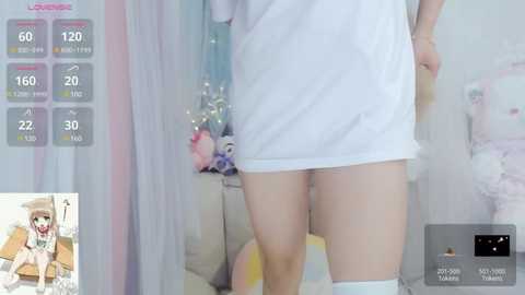 Media: A video of a woman in a white dress, seen from behind, in a pastel-colored room with soft lighting and various pastel-colored objects.