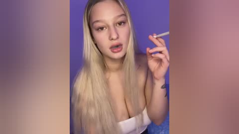 Media: Video of a young blonde woman with long hair, wearing a strapless top, smoking a cigarette against a purple background.