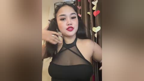 Media: A video of an East Asian woman with fair skin, wearing a sheer black halter top, red lipstick, and heart-shaped decorations.