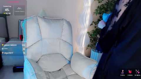 Media: Video of a modern living room with a white leather recliner, a green plant, a blue chair, and a dark jacket hanging on the wall.