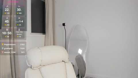 Media: Video of a minimalist room with a white leather armchair and a standing lamp with a clear glass shade, alongside a digital thermometer display.