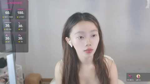 Media: Video of an East Asian woman with long, straight, dark hair, wearing a white top, sitting indoors. She has a light skin tone and a neutral expression.