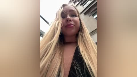 Media: A video of a young woman with long blonde hair, fair skin, and a black choker, standing in a dimly lit, industrial building with exposed beams and concrete walls.