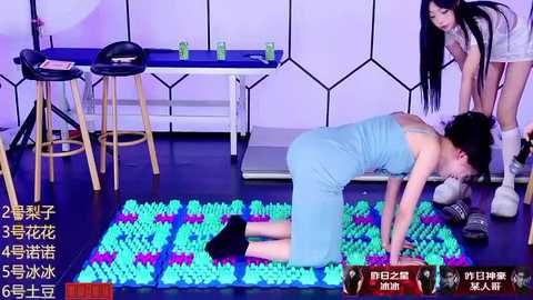 Media: Video of a young woman with dark hair and pale skin in a light blue tank top and shorts, doing yoga on a colorful mat in a modern studio with purple lighting, chairs, and a table.