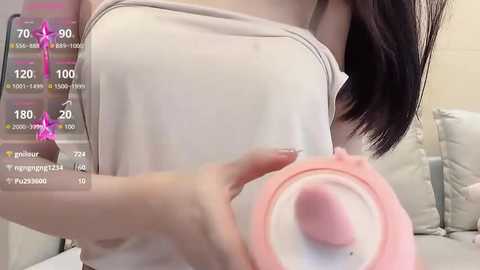 Media: A video of a woman with fair skin and long black hair, wearing a white tank top, using a pink vibrator, displayed in a virtual fitness app with exercise stats.