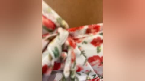 Media: A blurred, close-up video of a woman's face with light skin tone and undefined features, wearing a floral-patterned headband with red and green flowers. The background is out of focus, creating a soft, dreamy effect.