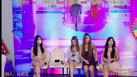 Media: Video of four Asian women seated on white chairs in a vibrant, colorful stage setting with large, abstract art and Chinese text.