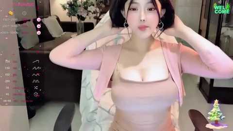 Media: A video of an East Asian woman with light skin and long black hair, wearing a pink jacket, adjusting her hair in a modern, well-lit living room.