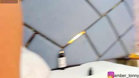 Media: Video of a modern bathroom with a gray, diamond-patterned wall, a white sink, and a bottle of hand sanitizer on the countertop.