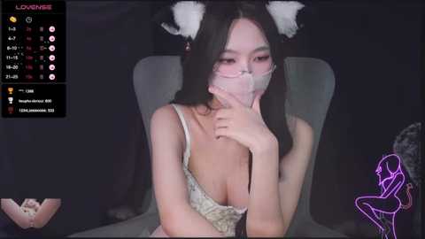 Media: A young East Asian woman with long black hair and white cat ears, wearing a white face mask, pink lingerie, and glasses, sits in a dimly lit room with a purple neon outline of a woman on the right.