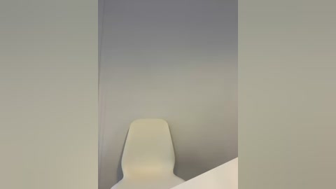 Media: A minimalist video featuring a single, modern white chair positioned in the center of a stark white room with a subtle gradient of light gray on the walls. The image conveys a clean, serene, and contemporary aesthetic.