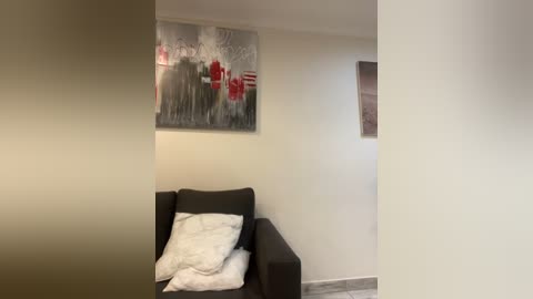 Media: Video of a minimalist living room with a black armchair, white pillow, and abstract art on the wall featuring red and black football players.