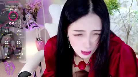 Media: Video of an Asian woman with long black hair, red lipstick, and red blouse, sitting in a studio with a white chair and a pink background.