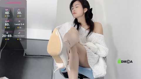 Media: A video of an Asian woman in a white off-shoulder sweater and beige heels, sitting on a chair, with a virtual fitness app interface overlaid.