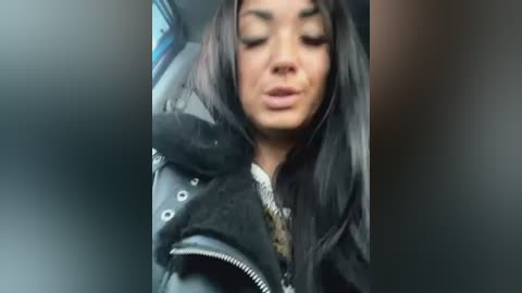 Media: A video shows a young woman with long, straight black hair, wearing a black leather jacket and a white shirt, sitting in a car, eyes closed.